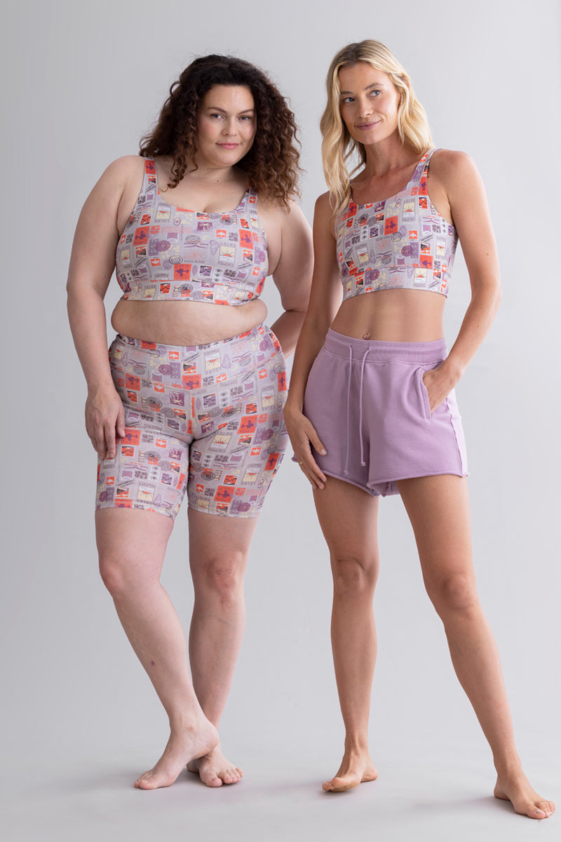 Two women in Hey Honey loungewear: one in a patterned crop top and biker shorts, the other in a matching top and lavender shorts.